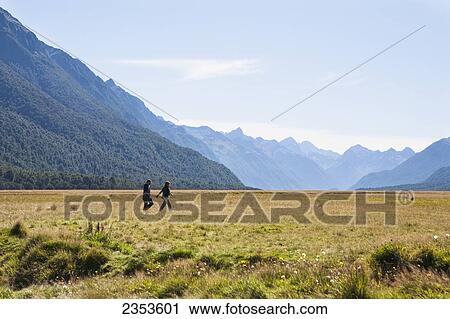 Stock Image - A Couple Explores The Vast Plains Surrounding New Zealand's Milford Sound National Park; Milford, New Zealand. Fotosearch