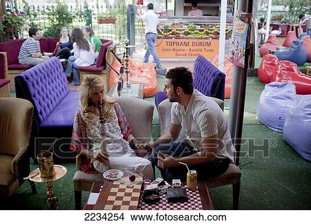 Picture - A couple get romantic in the Tophane Narghile Cafes which attract a younger crowd to hang out, smoke Narghile smoking pipe, drink tea and play backgammon, close to the Istanbul Modern, Istanbul, Turkey. Photo. Fotosearch