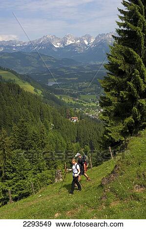 Stock Photo - A couple hiking in the Kitzbuehel alpine region with the Wilder Kaiser mountain ridge in the background. Tyrol, Austria.. Fotosearch