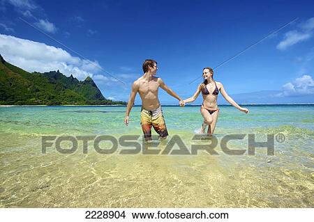 A couple holding hands and walking in the ocean water; Wailua, Hawaii, United States of America View Large Photo Image Picture - A couple holding hands and walking in the ocean water; Wailua, Hawaii, United States of America. Fotosearch