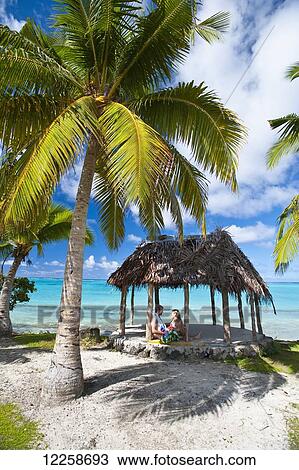 Stock Image - A couple in a beach fale (hut); Savaii Island, Samoa. Fotosearch