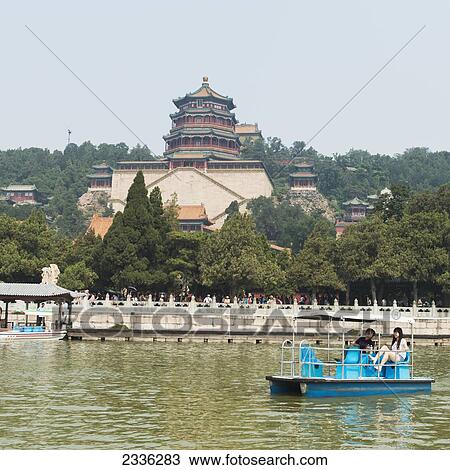 Stock Image - A Couple In A Boat On Kunming Lake With Tower Of Buddhist Incense In The Background At Summer Palace; Beijing, China. Fotosearch