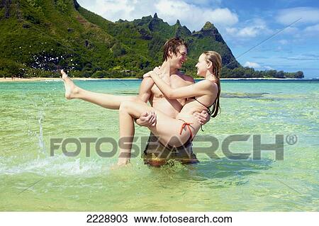 Stock Image - A couple in love standing in the ocean water; Wailua, Hawaii, United States of America. Fotosearch