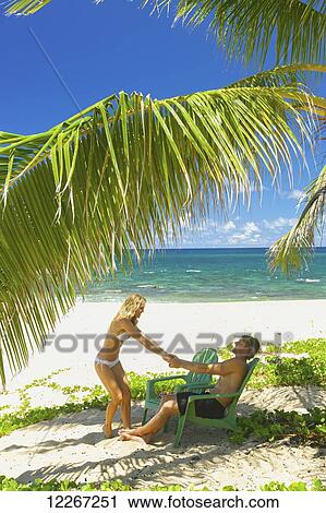 Stock Image - A couple in swimwear on the beach; Kauai, Hawaii, United States of America. Fotosearch