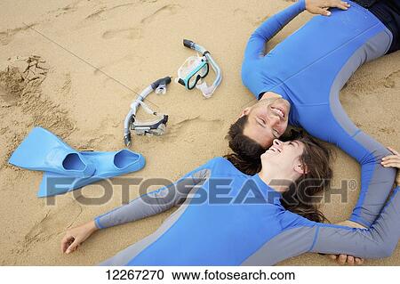 A couple lay on the sand with snorkelling gear, Lydgate Beach; Kauai, Hawaii, United States of America View Large Photo Image Stock Image - A couple lay on the sand with snorkelling gear, Lydgate Beach; Kauai, Hawaii, United States of America. Fotosearch