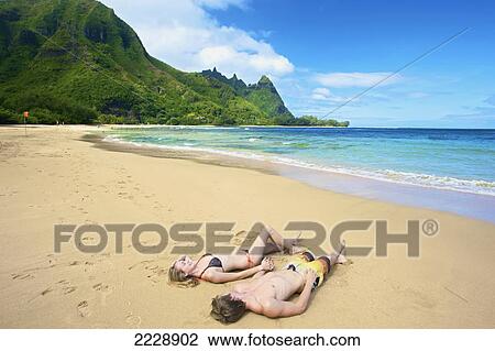 A couple laying in the sand at the water's edge; Wailua, Hawaii, United States of America View Large Photo Image Stock Image - A couple laying in the sand at the water's edge; Wailua, Hawaii, United States of America. Fotosearch