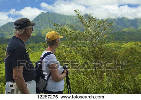 Stock Photography - A couple looks over the lush landscape on Kuilau Ridge Trail; Wailua, Kauai, Hawaii, United States of America. Fotosearch