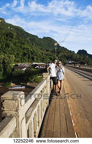 A couple poses on a bridge along the Ou River in a Northern Laos town; Nong Khiaw, Laos View Large Photo Image Stock Photograph - A couple poses on a bridge along the Ou River in a Northern Laos town; Nong Khiaw, Laos. Fotosearch