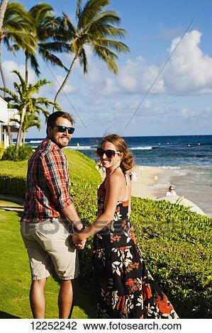 A couple poses on a lush lawn on Poipu beach; Poipu, Kauai, Hawaii, United States of America View Large Photo Image Stock Image - A couple poses on a lush lawn on Poipu beach; Poipu, Kauai, Hawaii, United States of America. Fotosearch