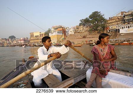 A couple rowing a boat in the River Ganges past the bathing ghats; Varanasi, India View Large Photo Image Stock Photo - A couple rowing a boat in the River Ganges past the bathing ghats; Varanasi, India. Fotosearch
