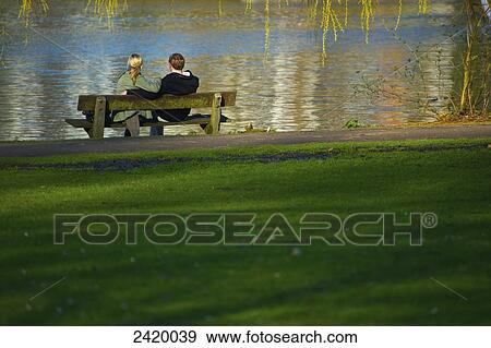 Stock Photo - A couple sits on a bench at the edge of the river; Hamburg, Germany. Fotosearch