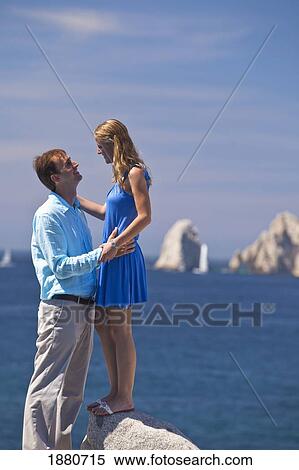 Stock Photography - A Couple Standing Together At The Water's Edge; Cabo San Lucas, Baja California, Mexico. Fotosearch