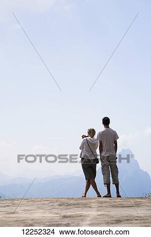 A couple stands at a lookout with a view over the valley between Luang Prabang and Vang Vieng; Laos View Large Photo Image Picture - A couple stands at a lookout with a view over the valley between Luang Prabang and Vang Vieng; Laos. Fotosearch
