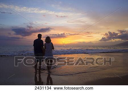 A couple stands on the beach at sunset; Wailea, Maui, Hawaii, United States of America View Large Photo Image Picture - A couple stands on the beach at sunset; Wailea, Maui, Hawaii, United States of America. Fotosearch