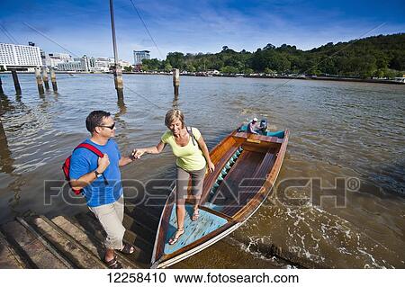 Stock Image - A couple taking a river boat ride; Bandar Seri Begawan, Brunei. Fotosearch