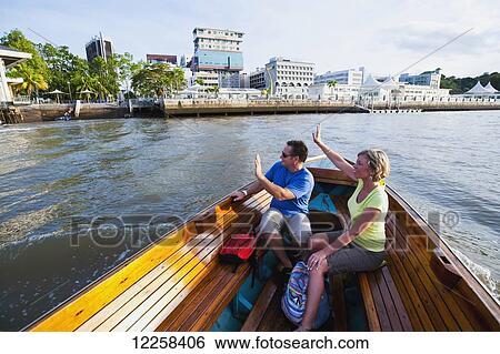 Stock Photograph - A couple taking a river boat ride; Bandar Seri Begawan, Brunei. Fotosearch