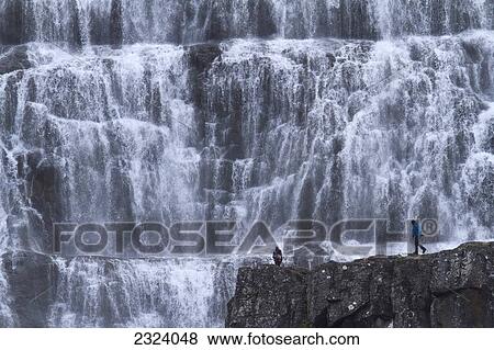 A couple walk in front of the waterfall Dynjandi; Westfjords, Iceland View Large Photo Image Stock Photo - A couple walk in front of the waterfall Dynjandi; Westfjords, Iceland. Fotosearch