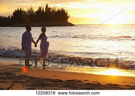 Stock Photograph - A couple walking on the beach at sunset at the Empire Hotel and Country Club; Bandar Seri Begawan, Brunei. Fotosearch