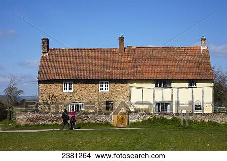 Picture - A couple walks by a house with two different facades; Frampton upon Severn, Gloucestershire, England. Fotosearch