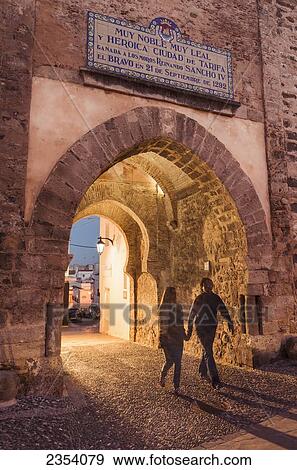 Stock Photo - A Couple Walks Hand In Hand Through Puerta De Jerez; Tarifa, Cadiz, Andalusia, Spain. Fotosearch