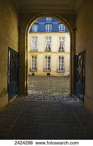 Stock Photo - A covered walkway with an arched entrance and doorways, Marais district; Paris, France. Fotosearch
