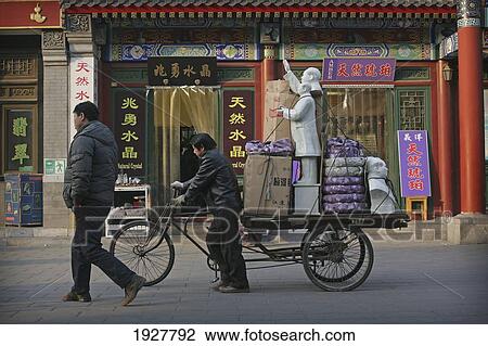 Stock Image - A Cycle Rickshaw Driver Carries Statues Of Chairman Mao Zedong From Panjiayuan Flea Market, Beijing's Largest Antique Market, Beijing, China. Fotosearch