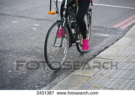 Stock Photo - A cyclist with bright pink shoes; London, England. Fotosearch