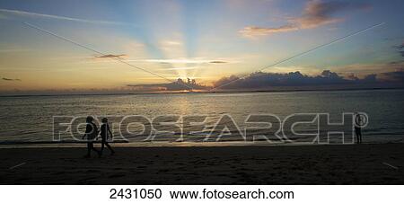 Stock Image - A dramatic sunset while walking on the beach; Mauritius. Fotosearch