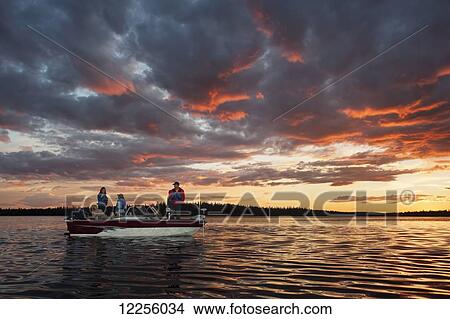 A family fishing from their motorboat on a calm lake at sunset in Northern Ontario; Ontario, Canada View Large Photo Image Picture - A family fishing from their motorboat on a calm lake at sunset in Northern Ontario; Ontario, Canada. Fotosearch
