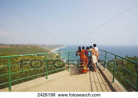 Stock Photo - A family stands at a railing looking out over the water; Visakhapatnam, Andhra Pradesh, India. Fotosearch