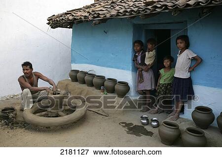 Stock Photo - A family stands outside their blue house with pots on display outside, Potters village; Madhya Pradesh, India. Fotosearch