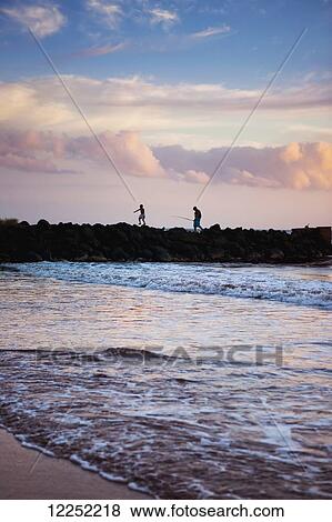Stock Photo - A father and son fishing off the jetty at Pakala's; Kauai, Hawaii, United States of America. Fotosearch
