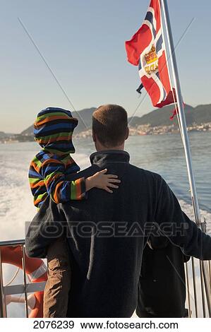 Stock Photo - A Father And Son Ride On The Back Of A Boat; Fjord Norway. Fotosearch