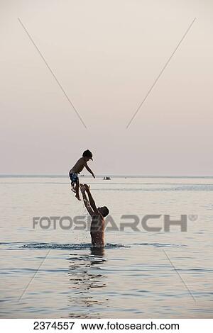A father standing in the water and throwing his son into the air; Puglia, Italy View Large Photo Image Stock Photo - A father standing in the water and throwing his son into the air; Puglia, Italy. Fotosearch