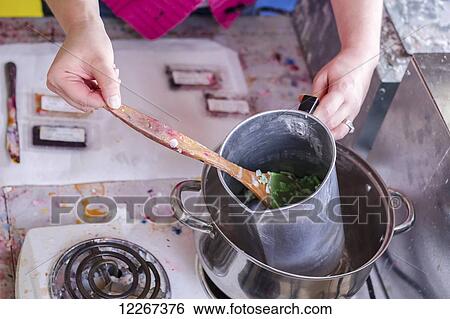 Stock Photograph - A female craft maker demonstrates the process to make soy candles at home, showing the wax melting on a stove in this step by step process; Fort McMurray, Alberta, Canada. Fotosearch