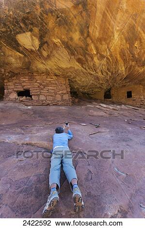 Stock Image - A female tourist takes photos with a smart phone of the House on Fire Anasazi ruin in Mule Canyon; Utah, United States of America. Fotosearch