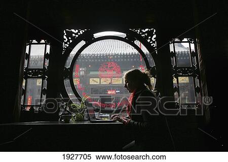 Stock Photography - A Female Tourist Using The Internet On A Laptop In A Guesthouse In Pingyao, A Unesco World Heritage Site, Shanxi Province, China. Fotosearch
