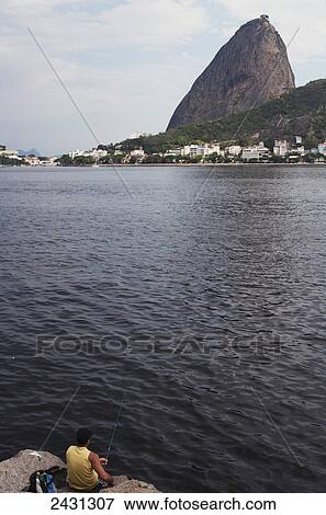 A fisherman with a view of Sugarloaf mountain; Rio de Janeiro, Brazil View Large Photo Image Stock Photo - A fisherman with a view of Sugarloaf mountain; Rio de Janeiro, Brazil. Fotosearch