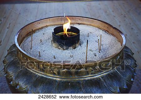 Stock Image - A flame and burning incense; Japan. Fotosearch