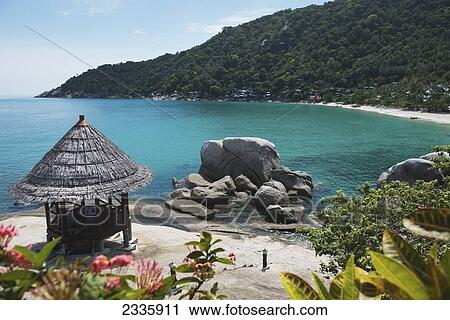 Stock Image - A Gazebo On The Beach And A Rock Formation At The Water's Edge With A View Of The Coastline. Fotosearch