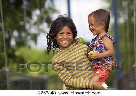 A girl holding her young cousin; Battambang, Cambodia View Large Photo Image Stock Photo - A girl holding her young cousin; Battambang, Cambodia. Fotosearch