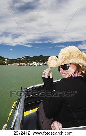 Stock Image - A Girl Holds Her Cowboy Hat On A Boat Cruise From Russell To Paihia; New Zealand. Fotosearch