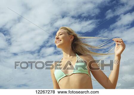 Stock Photo - A girl in a bikini top with long blond hair blowing in the wind; Kauai, Hawaii, United States of America. Fotosearch