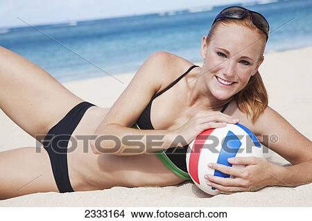 A girl in a two piece bathing suit laying on the sand with a volleyball; Waikiki, Hawaii, United States of America View Large Photo Image Picture - A girl in a two piece bathing suit laying on the sand with a volleyball; Waikiki, Hawaii, United States of America. Fotosearch