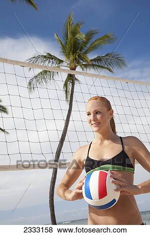 Stock Photo - A girl in a two piece bathing suit ready to play beach volleyball; Waikiki, Hawaii, United States of America. Fotosearch