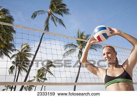 Stock Photo - A girl in a two piece bathing suit ready to play beach volleyball; Waikiki, Hawaii, United States of America. Fotosearch