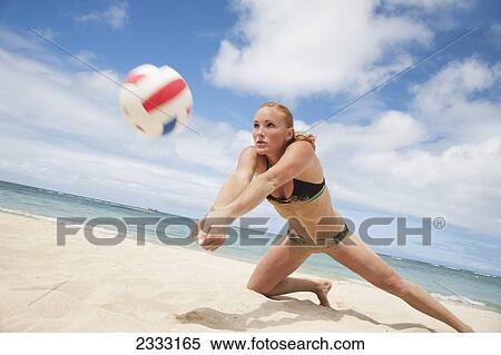 Stock Photography - A girl in a two piece bathing suit playing beach volleyball; Waikiki, Hawaii, United States of America. Fotosearch