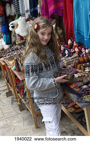 Stock Image - A Girl Looks At Peruvian Handicrafts; Chinchero Peru. Fotosearch