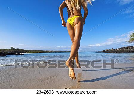 A girl running down the beach in a yellow bikini; Big Island, Hawaii, United States of America View Large Photo Image Stock Image - A girl running down the beach in a yellow bikini; Big Island, Hawaii, United States of America. Fotosearch
