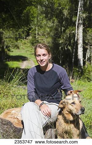 Stock Photo - A Girl Sits Relaxing Outside On A Warm Summers Day With Her Dog At Blue Duck Lodge, In Whanganui National Park; Whakahoro, New Zealand. Fotosearch